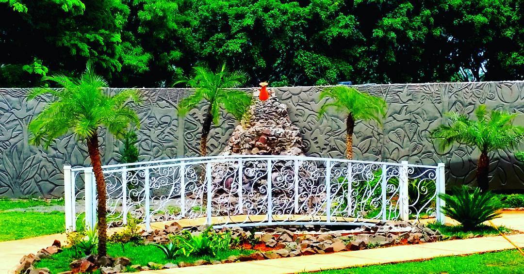 Área externa arborizada com jardim e fonte
